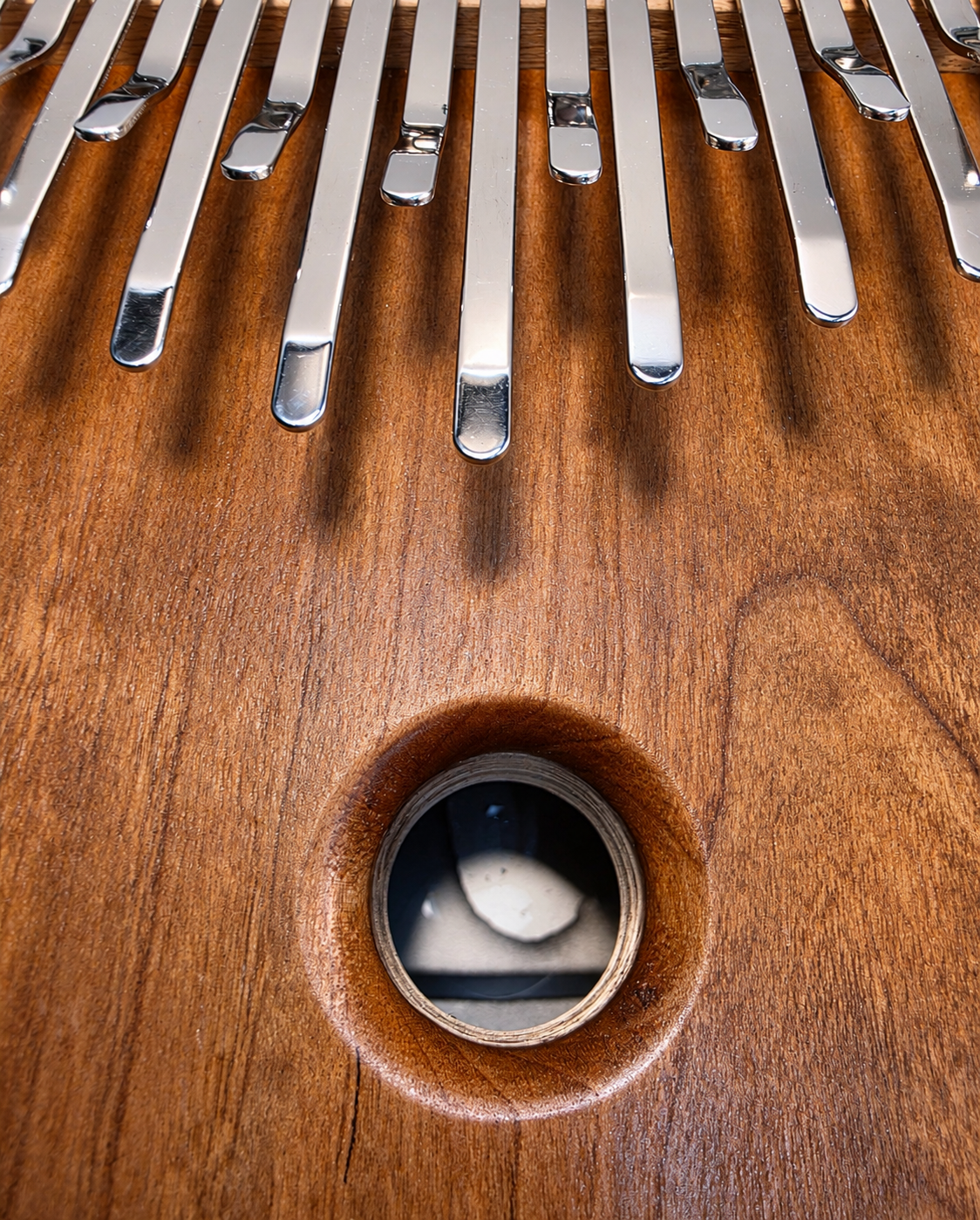 Detalle de las láminas de acero y el orificio de sonido sobre madera de nogal